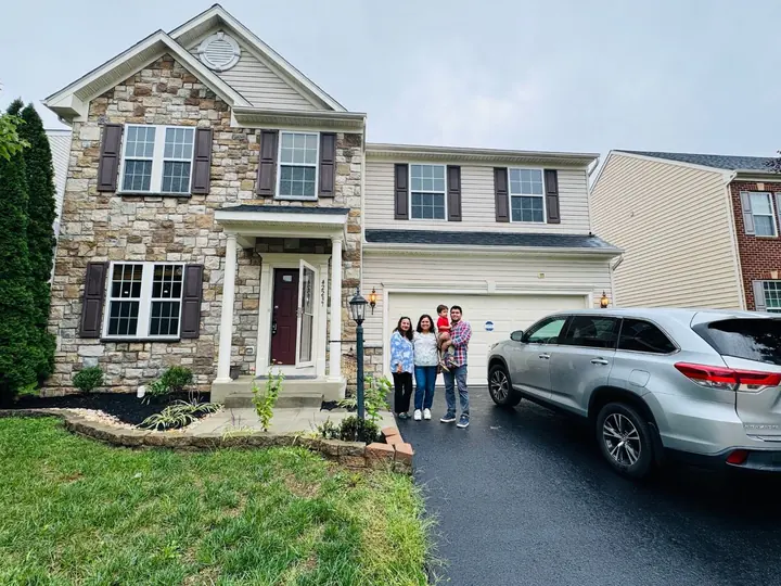 Family standing in front of their new stone-front home