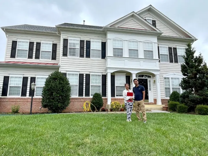 Couple standing on the lawn in front of their new home